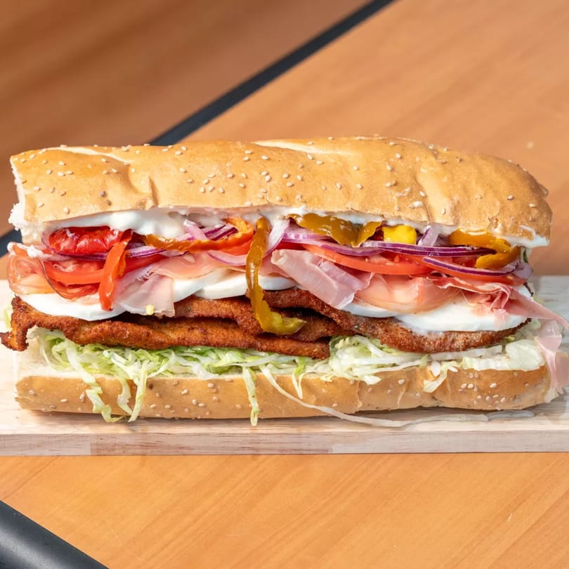 A large Capones Italian Eatery West deli sandwich with fried cutlets, prosciutto, mozzarella, and vegetables.